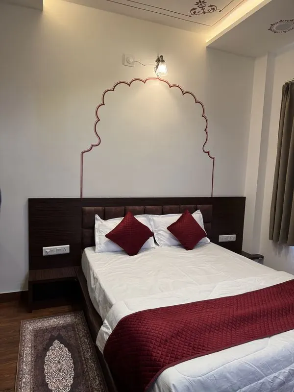 Room with a hand-painted maroon mehrab arch above the bed