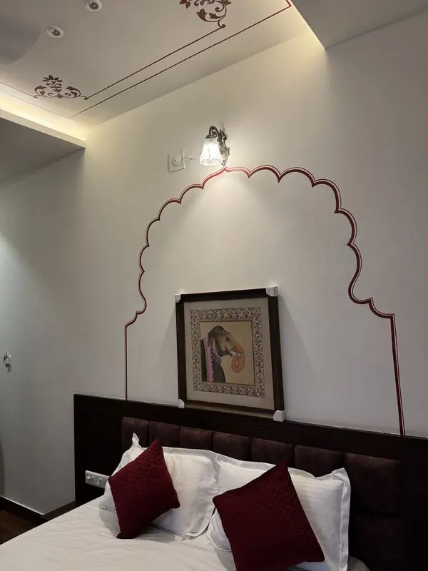 A framed miniature painting set within a hand-painted arch above the bed