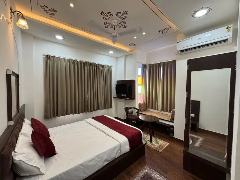 A spacious room with curtained windows, a window seat and a full-length mirror